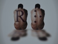 due persone che portano sulla schiena la lettera R in nero e in braille